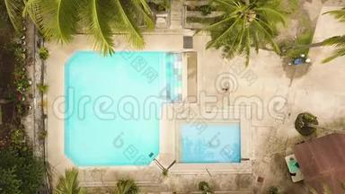 热带度假酒店的无人机景游泳池。 年轻人在蓝水游泳池游泳，暑假在